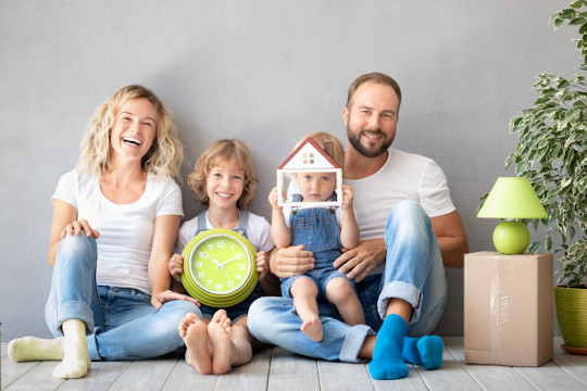 Happy family with two kids playing into new home. Father, mother and children having fun together. Moving house day and real estate concept